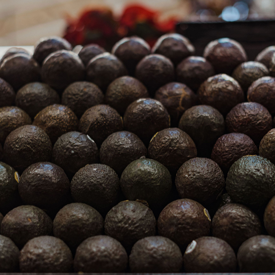 close up of neatly stacked, ripe avocados on store shelf